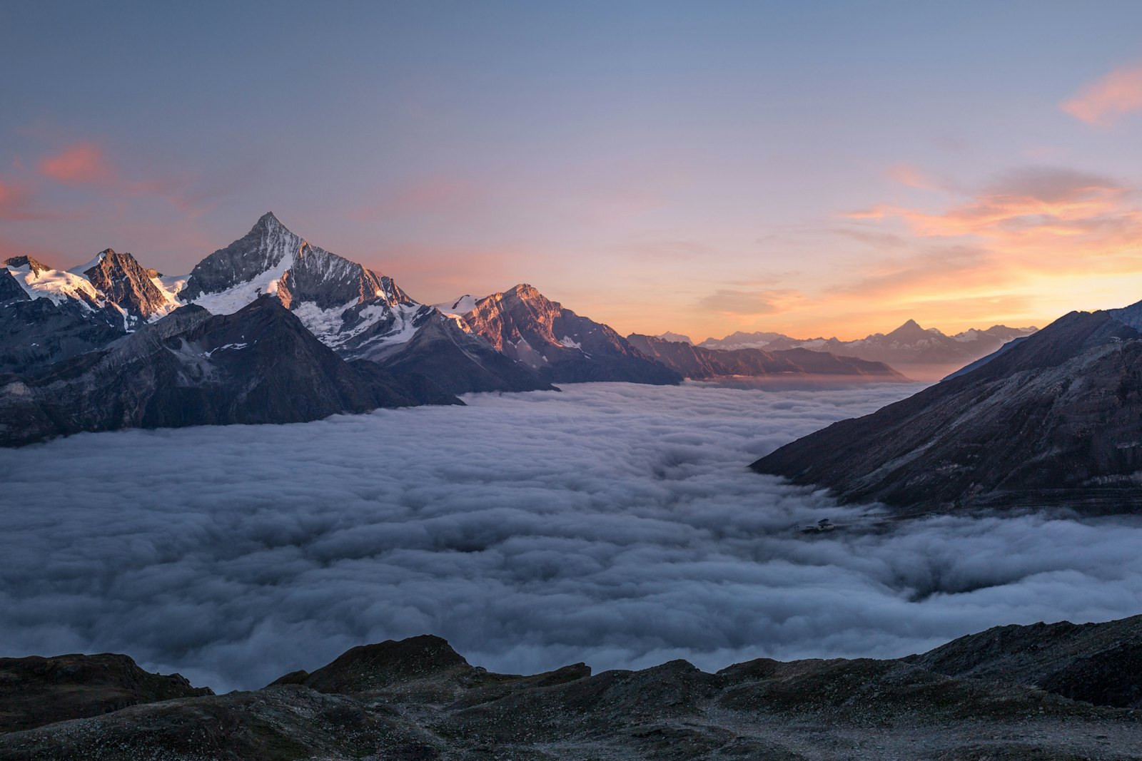 Mist rolling over dramatic mountain peaks at dawn